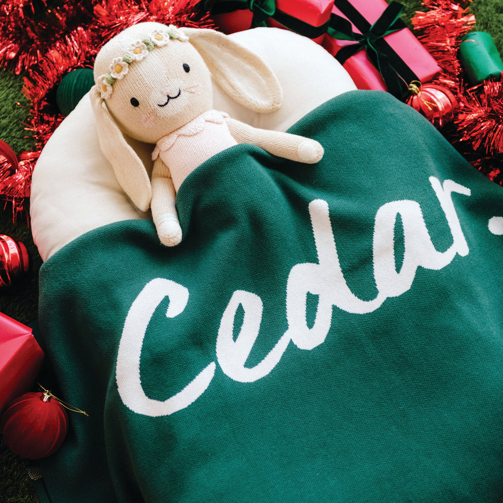 
                  
                    Load image into Gallery viewer, Green blanket with the name &amp;#39;Cedar&amp;#39; knitted into design, plush bunny toy, and Christmas decorations.
                  
                