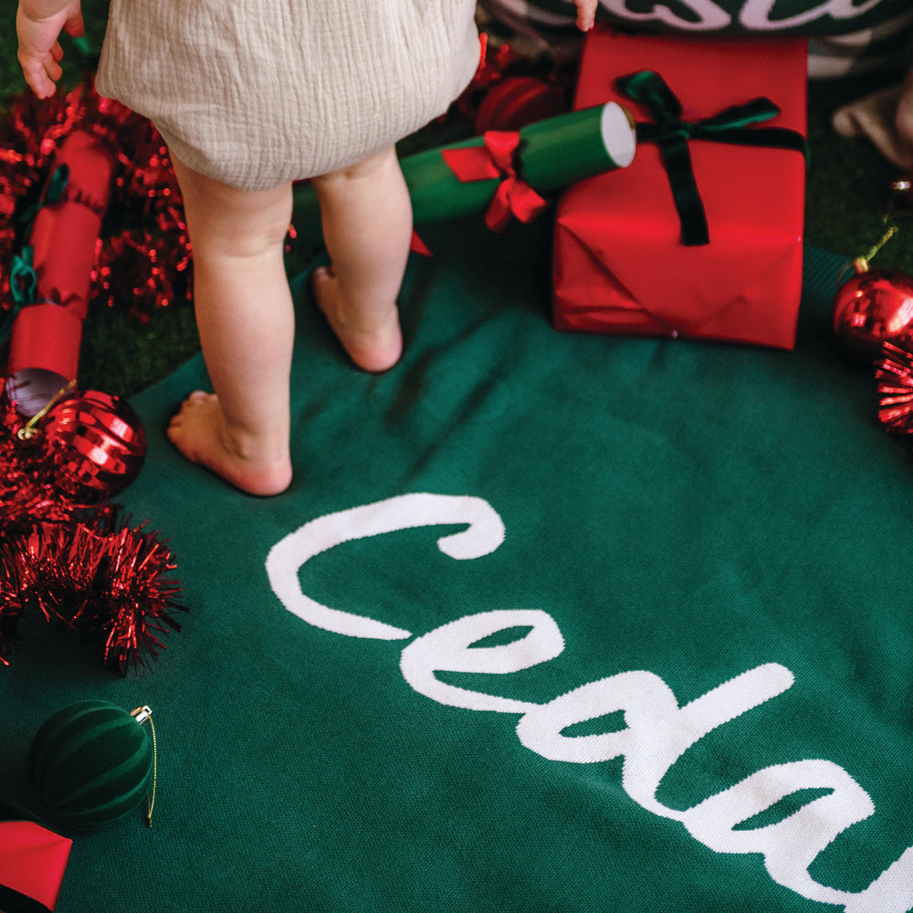 
                  
                    Load image into Gallery viewer, Green blanket with name &amp;#39;Cedar&amp;#39; knitted into it, surrounded by Christmas decorations.
                  
                